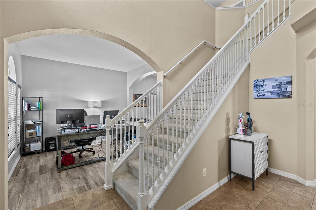 A staircase with white railings sits beside an arched entryway leading to a home office — 11714 GREAT COMMISSION WAY, ORLANDO, FL