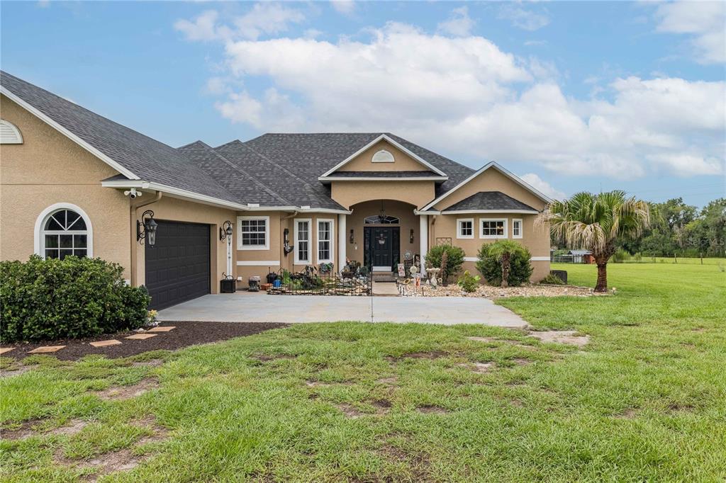 A single-story tan house with a dark shingled roof sits behind a gravel driveway — 4280 TURNER ROAD, MULBERRY, FL