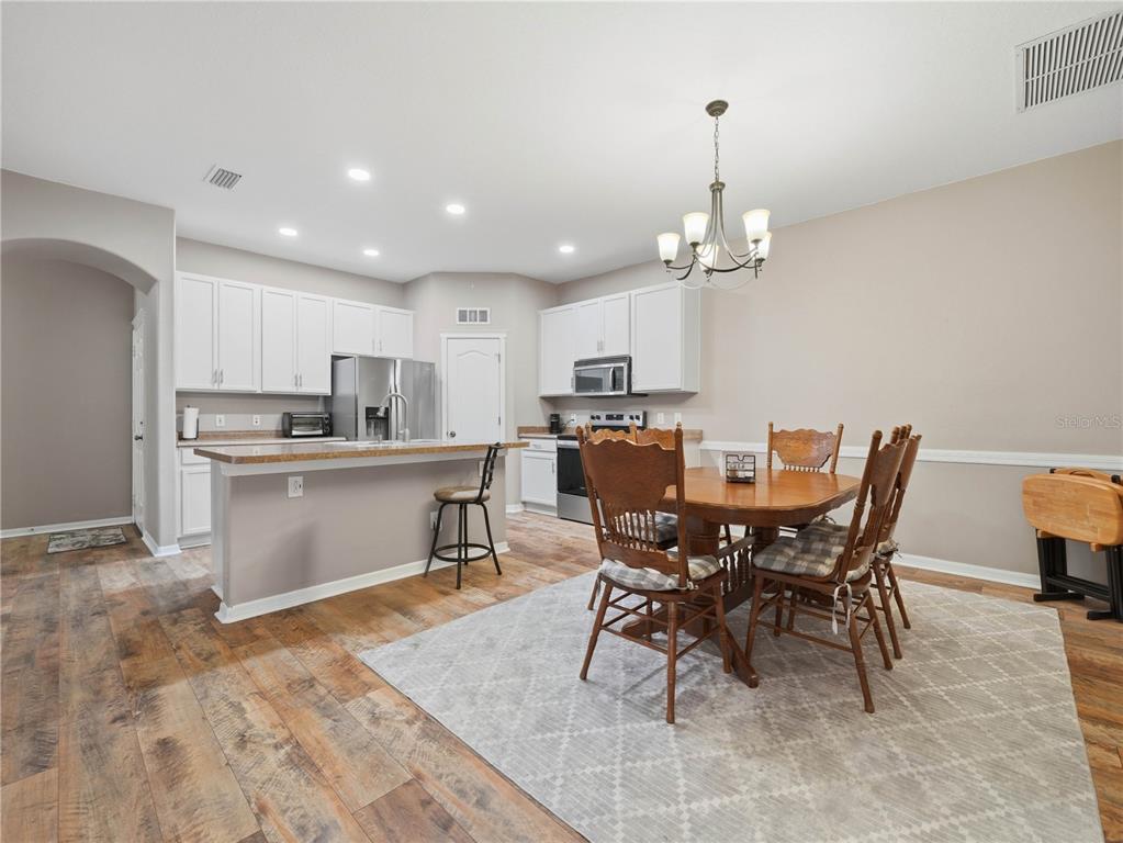 A kitchen with white cabinets and a dining area with a wooden table and chairs — 6936 SURREY OAK DRIVE, APOLLO BEACH, FL