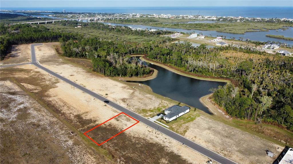 An aerial view shows a vacant rectangular lot outlined in red along a paved road — 197 STILLWATER DRIVE, FLAGLER BEACH, FL