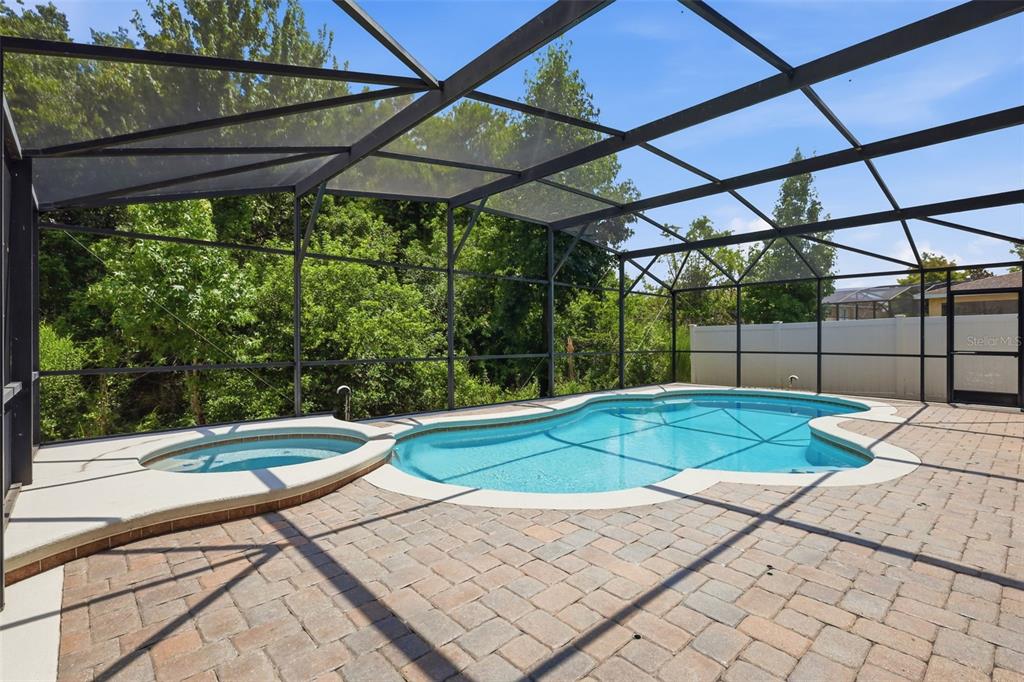 A screened-in swimming pool and hot tub on a paved patio surrounded by trees — 2555 SAND ARBOR CIRCLE, ORLANDO, FL