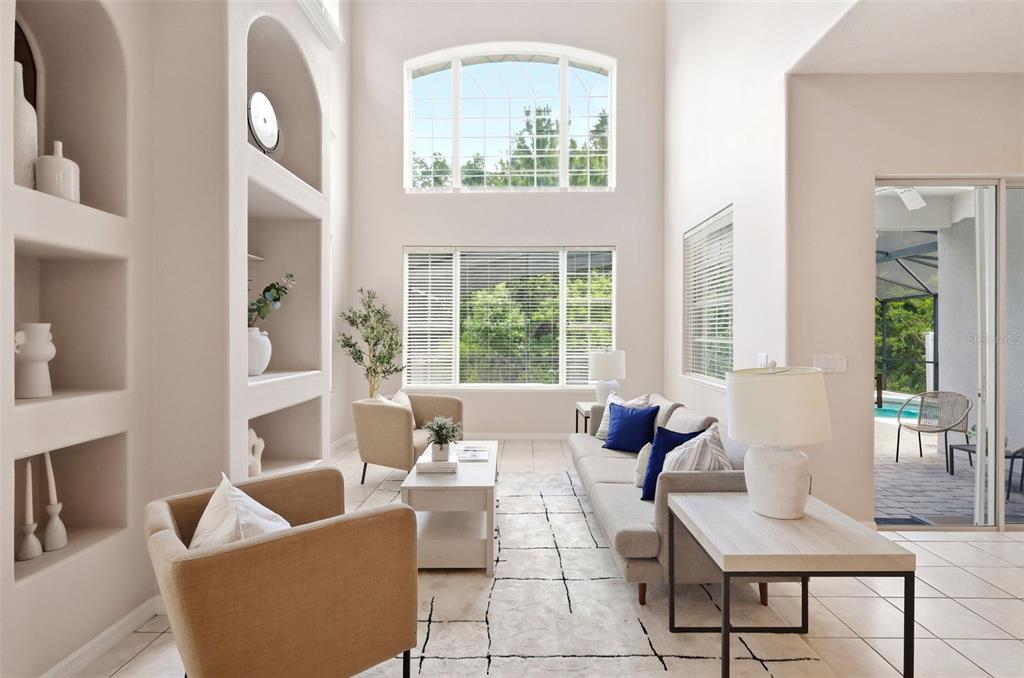 A bright, open-concept living and dining area features high ceilings, tile floors, and large windows — 2555 SAND ARBOR CIRCLE, ORLANDO, FL