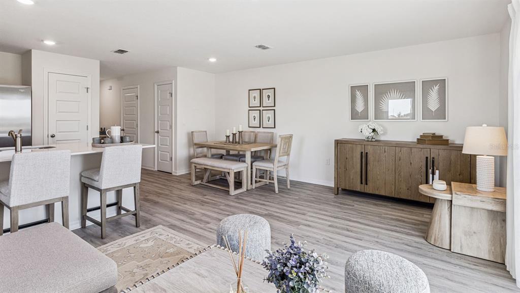 An open-concept dining and living area features light wood flooring, neutral walls, and modern furniture — 2334 AVEENO AVENUE, HAINES CITY, FL