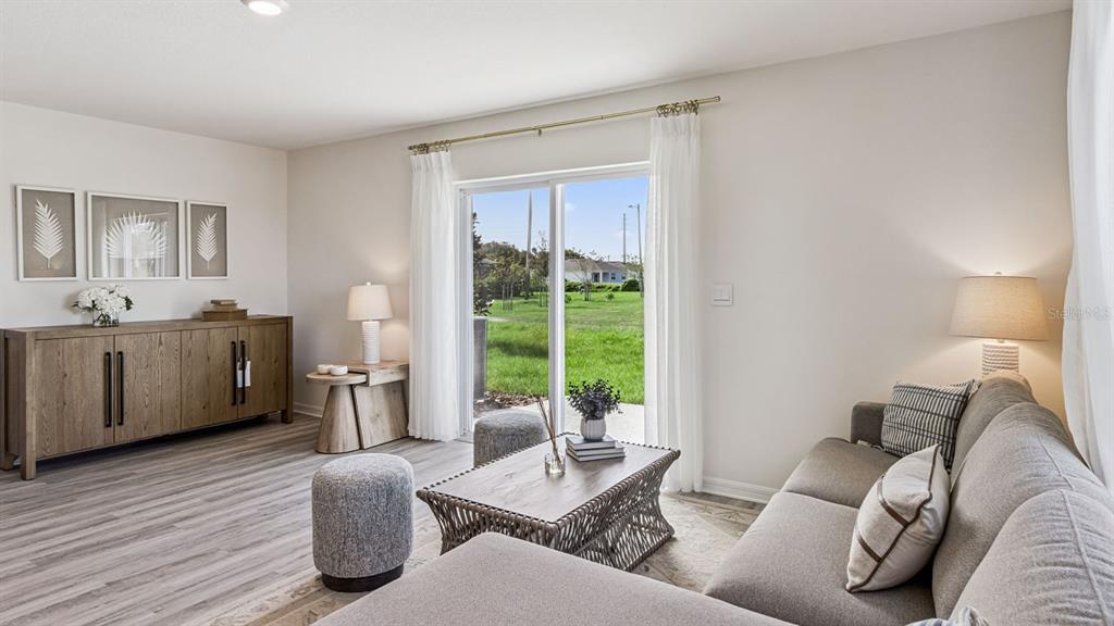 A living room features a gray sofa, wood console, coffee table, and sliding glass doors — 2334 AVEENO AVENUE, HAINES CITY, FL