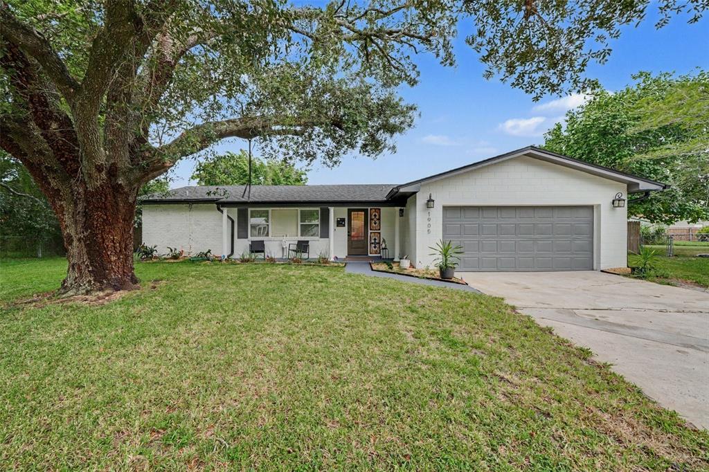 A single-story house with a white brick exterior, gray garage door, and a large oak tree — 1905 BONANZA CT, WINTER PARK, FL