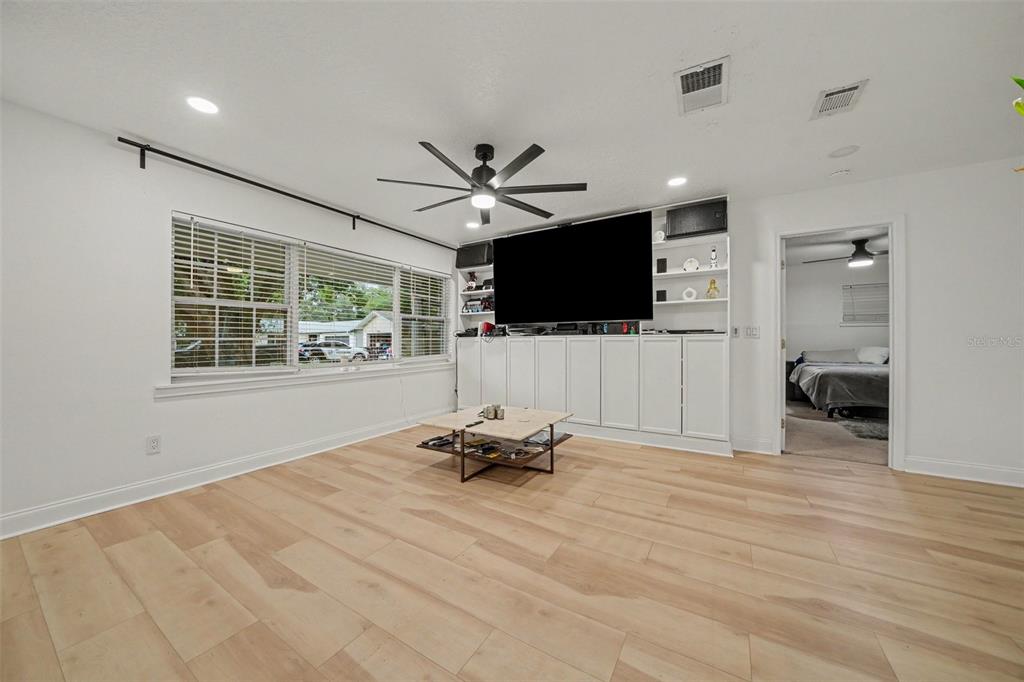 A living room features light wood flooring, a large built-in media center, and a ceiling fan — 1905 BONANZA CT, WINTER PARK, FL