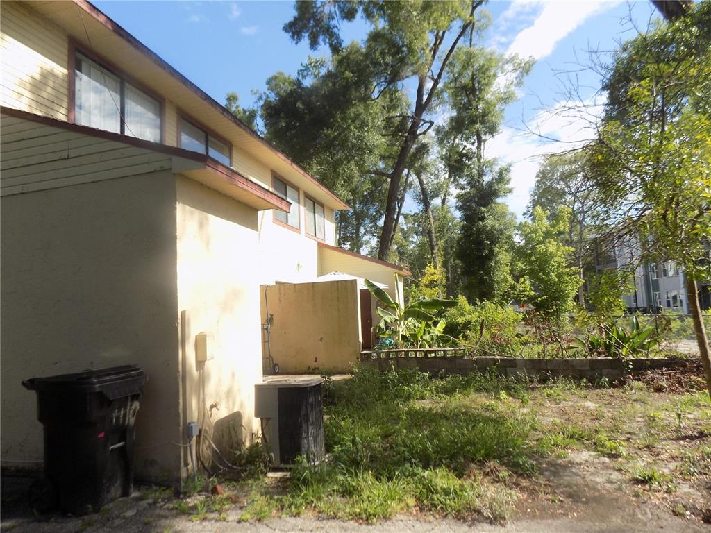 A yellow two-story house exterior with a black trash bin and an air conditioning unit — 1110 SW 62 TERRACE UNIT A,B,C,D,E and F, GAINESVILLE, FL