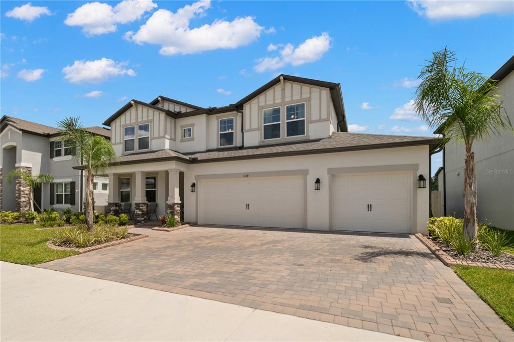 A two-story suburban house features a paved driveway, three-car garage, and a covered front porch — 3134 MARINE GRASS DRIVE, WIMAUMA, FL