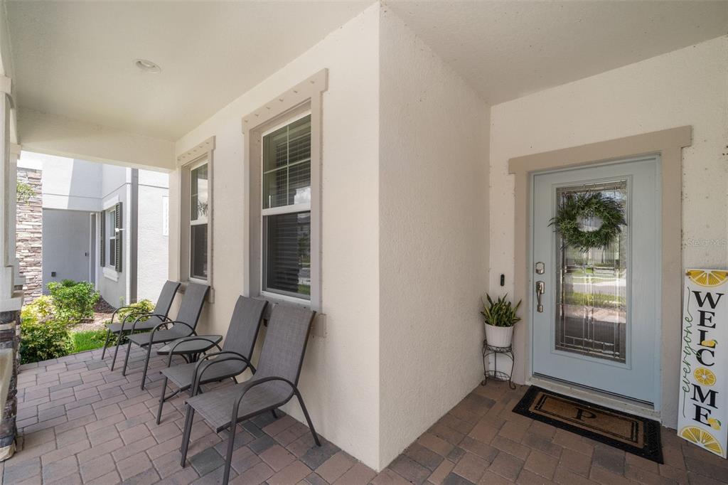 A covered front porch features a light blue door, four gray chairs, and brick pavers — 3134 MARINE GRASS DRIVE, WIMAUMA, FL