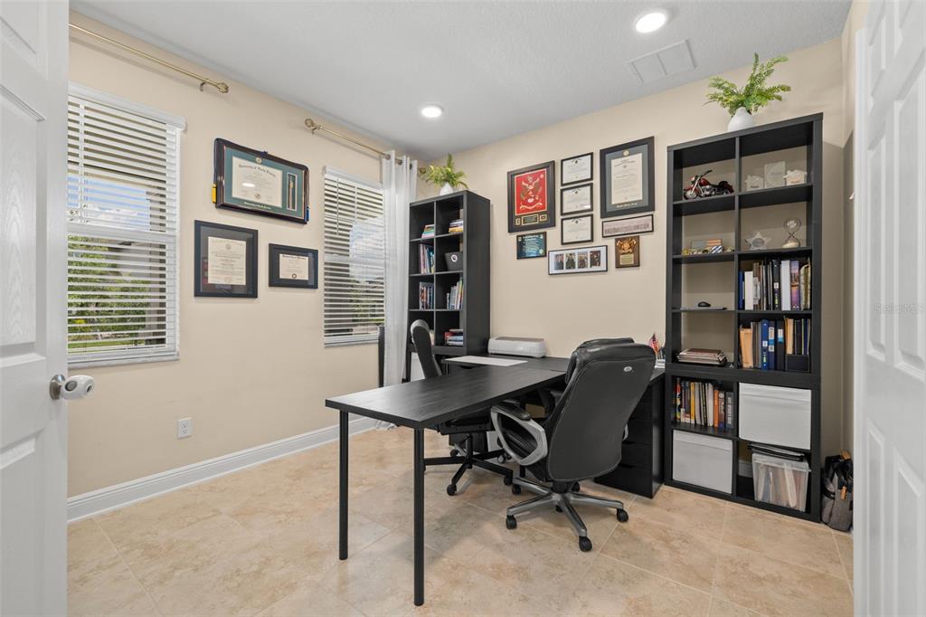 A home office features a black desk, matching shelving units, tiled floors, and framed wall art — 3134 MARINE GRASS DRIVE, WIMAUMA, FL