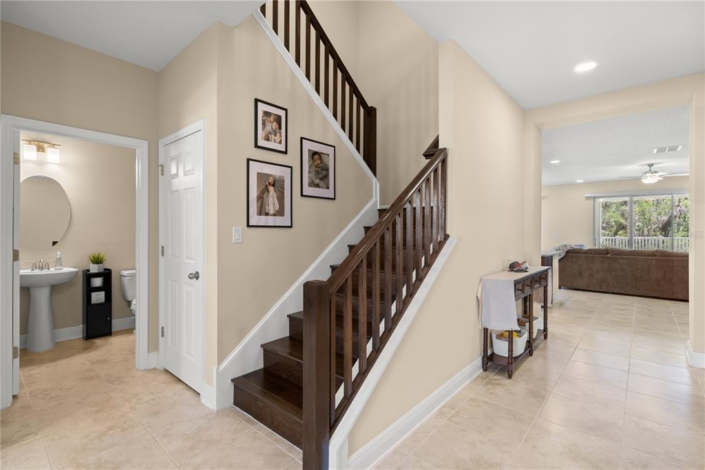 An entryway features a staircase with dark wood steps and railings, tile flooring, and a bathroom — 3134 MARINE GRASS DRIVE, WIMAUMA, FL