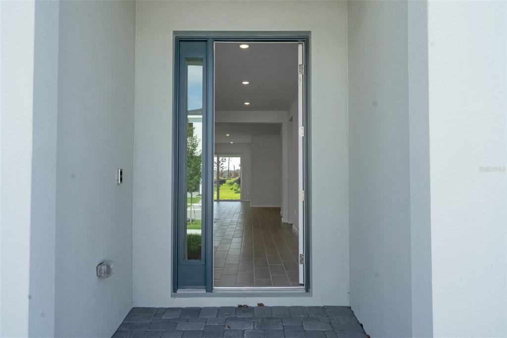 A view through an open front door showing a tiled entryway and a rear sliding door — 5461 NW CAMBERLY COURT, PORT ST LUCIE, FL