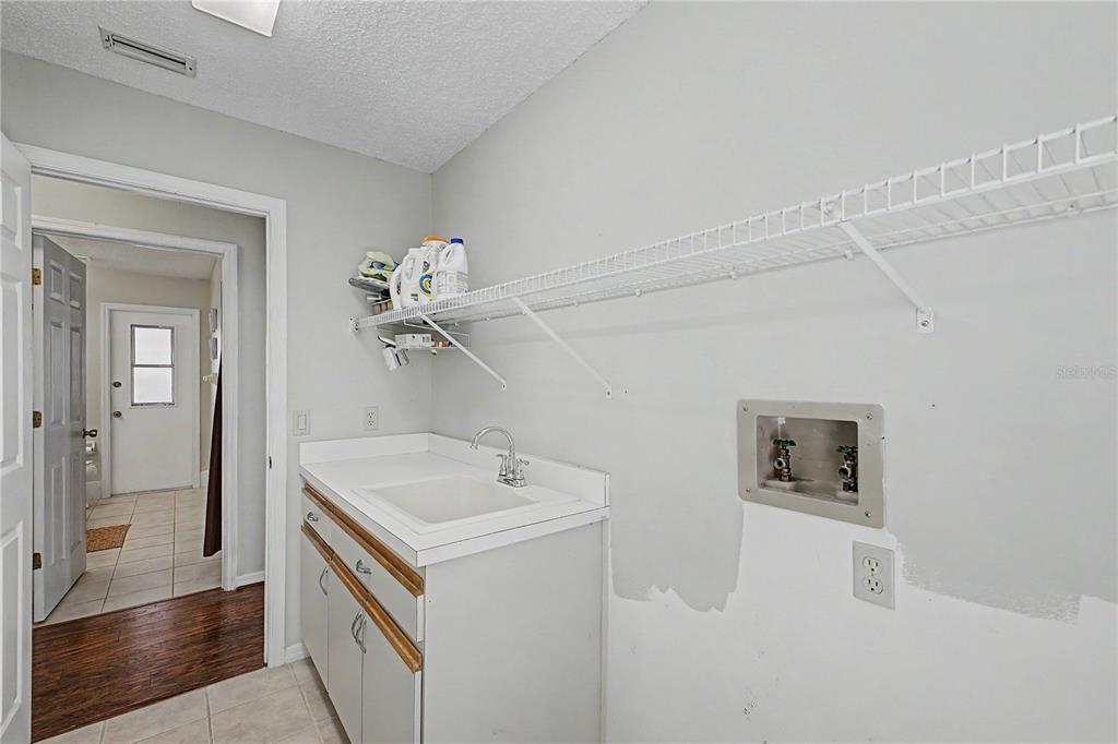A single-story house with a beige exterior, a covered entryway, and a large tree nearby — 1364 OVERLAND DRIVE, SPRING HILL, FL