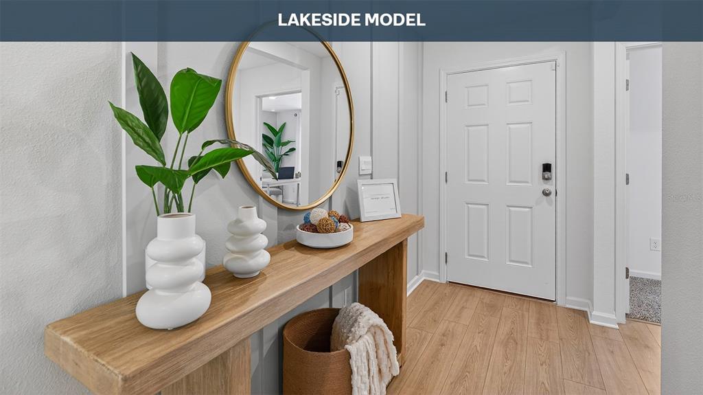 An entryway features a wooden console table, a round mirror, and a white front door — 18 SAWDUST LANE, PALM COAST, FL