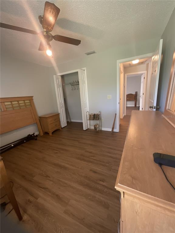 A bedroom features wood-look flooring, a ceiling fan, a closet, and a wooden headboard — 1440 ALBERNI STREET NW, PALM BAY, FL