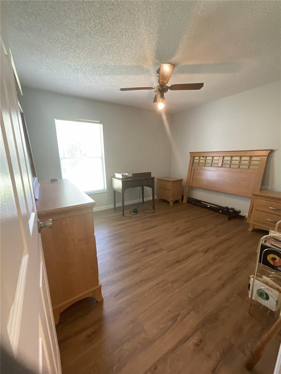 A bedroom with wood-look flooring, a ceiling fan, a wooden headboard, and a small desk — 1440 ALBERNI STREET NW, PALM BAY, FL