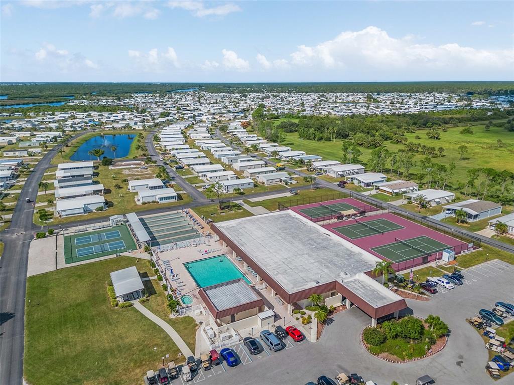 Aerial view of a residential community featuring a swimming pool, tennis courts, and parking lot — 514 MADONNA, NORTH PORT, FL
