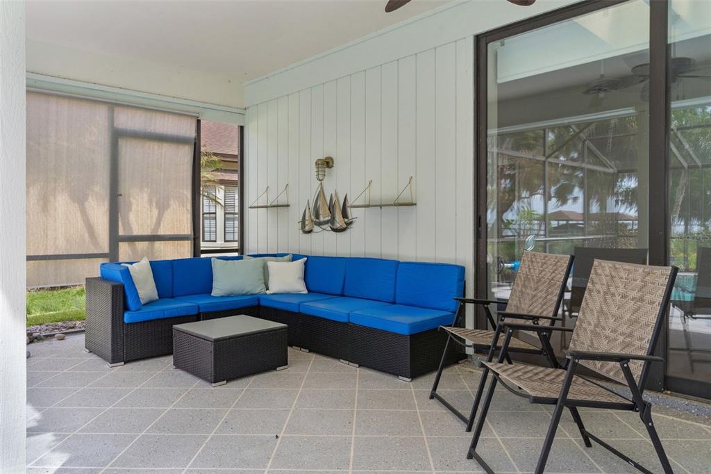 A screened-in patio features a blue sectional sofa, a coffee table, and two outdoor chairs — 60 SAND LAKE PLACE, EUSTIS, FL