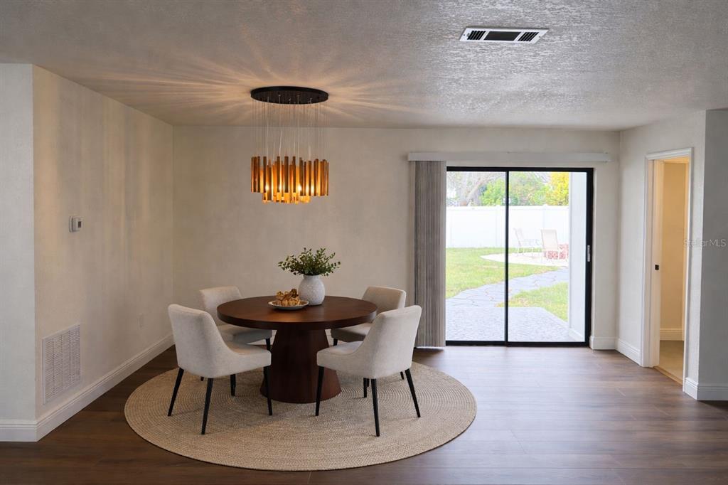 A dining room features a round wooden table, four chairs, and a modern pendant light — 343 SHORE DRIVE E, OLDSMAR, FL