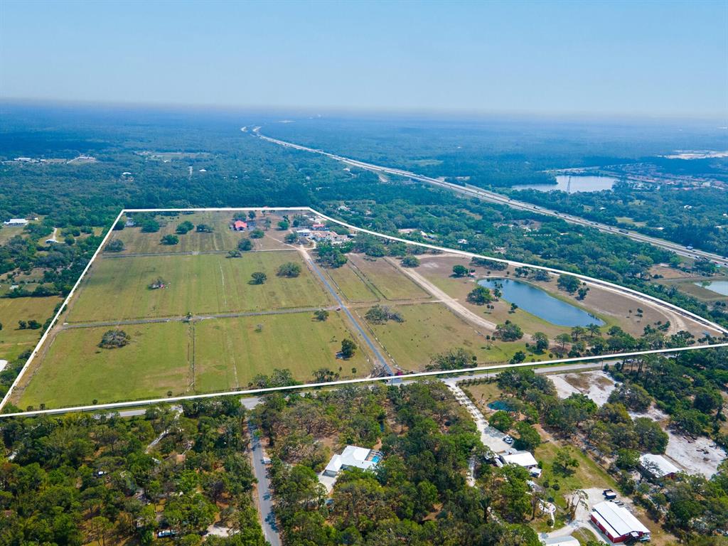 An aerial view shows a large, fenced rural property with a pond and several buildings — 0396014400, VENICE, FL