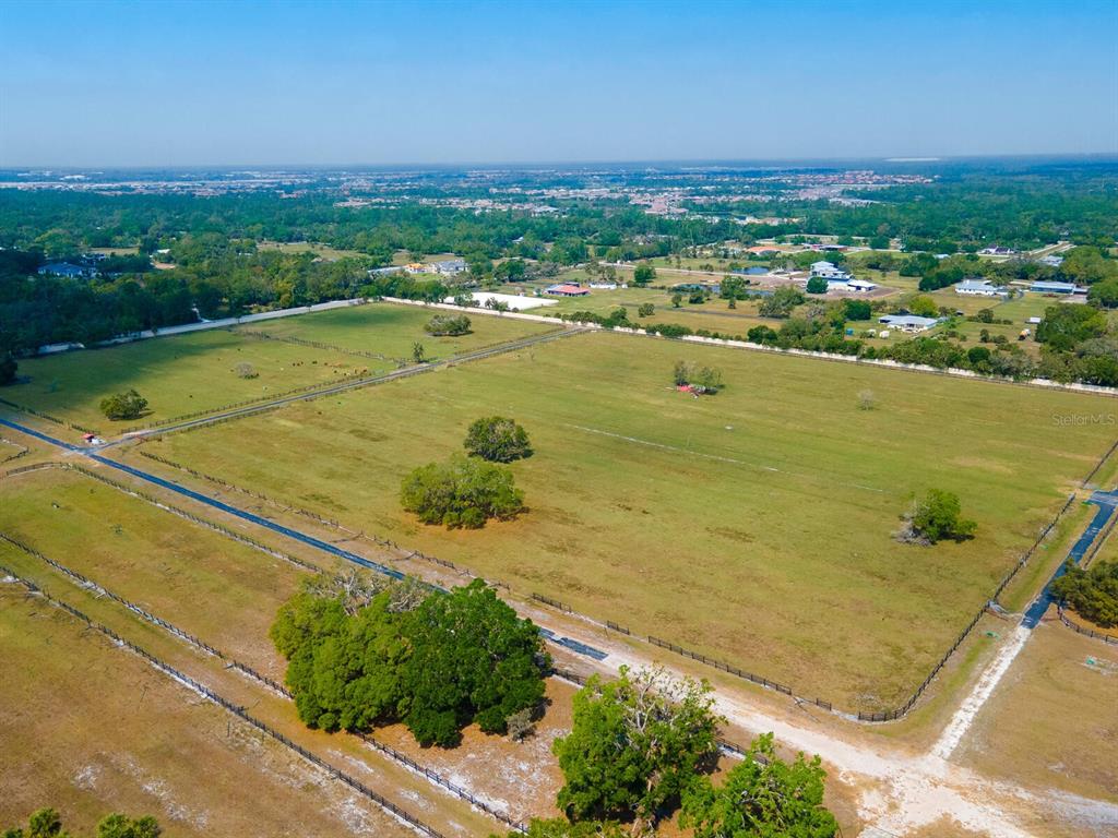 An aerial view shows a large, fenced grassy pasture with scattered trees and surrounding rural landscape — 0396014400, VENICE, FL