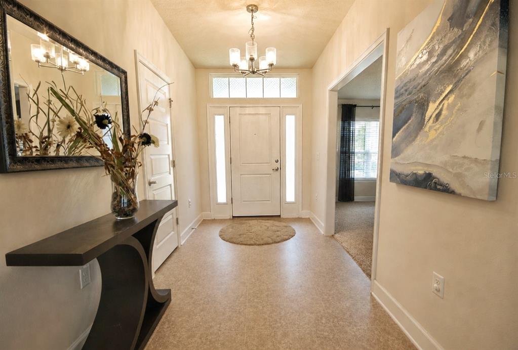 A covered entryway features a dark brown front door with sidelights and a transom window — 7733 SLOEWOOD DRIVE, LEESBURG, FL