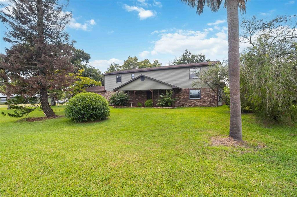 A two-story house with gray siding, a stone facade, and a covered front porch — 4899 SPARROW DRIVE, ST CLOUD, FL