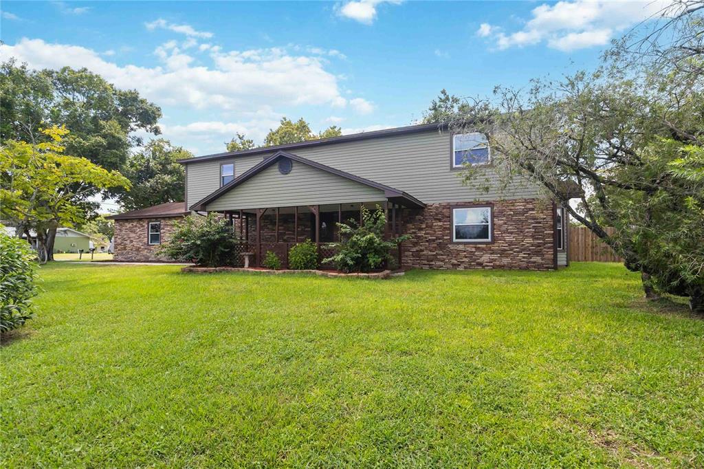 A two-story house with green siding, a stone facade, and a screened-in front porch — 4899 SPARROW DRIVE, ST CLOUD, FL