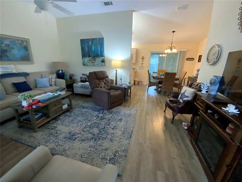 A living room with a beige sofa, brown recliner, area rug, and adjacent dining area — 9486 SE 173RD PLACE, SUMMERFIELD, FL