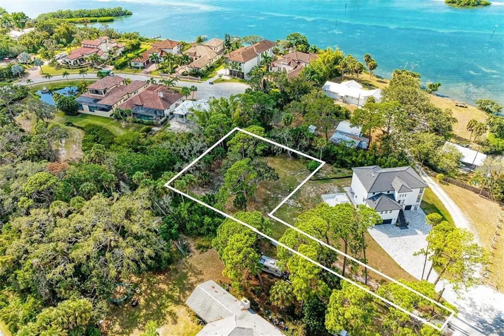 An aerial view shows a vacant, wooded residential lot outlined in white near the water — 0 ROBERTS RD. ROAD, NOKOMIS, FL