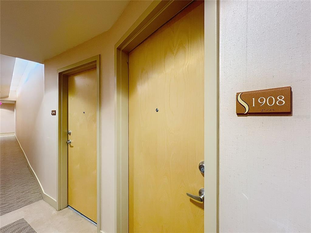 A hallway features two light wood doors with metal hardware and a room number sign — 155 S COURT AVENUE UNIT 1908, ORLANDO, FL