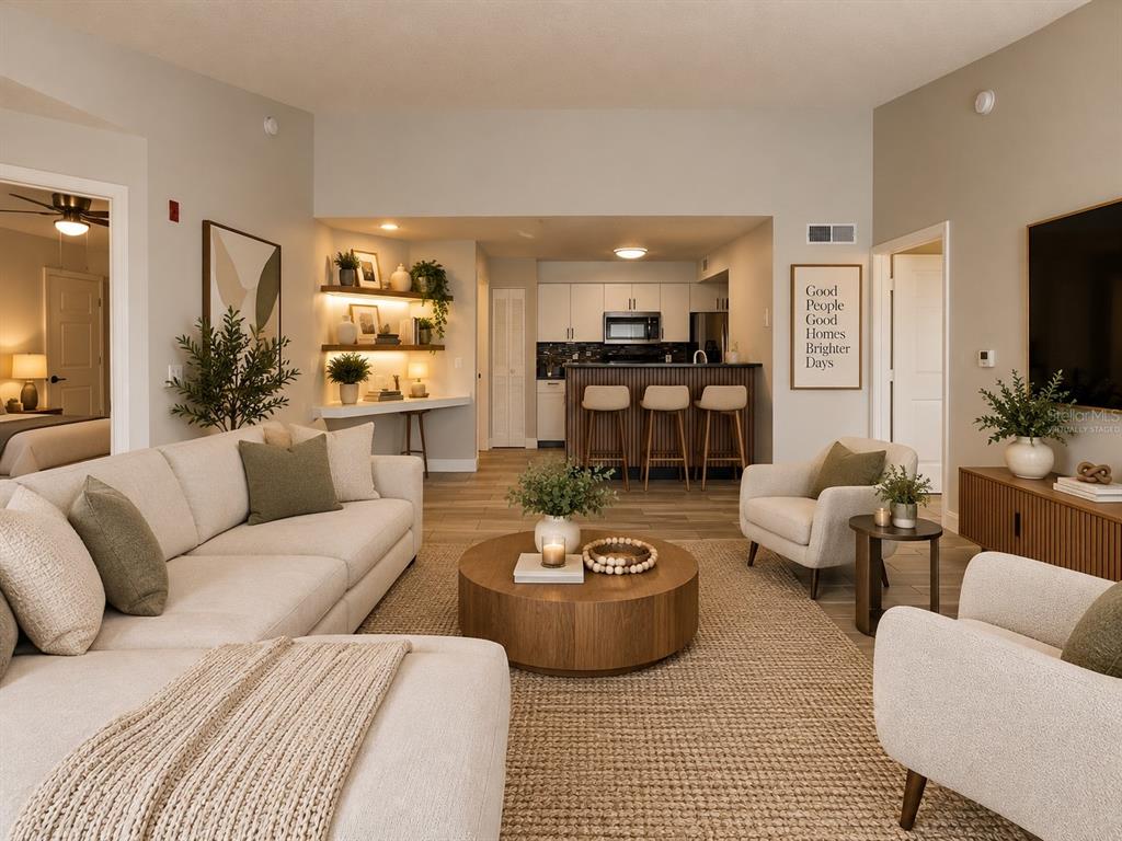 A kitchen features white cabinets, a black countertop, stainless steel appliances, and wood-look tile flooring — 2208 ANTIGUA PLACE UNIT 938, KISSIMMEE, FL