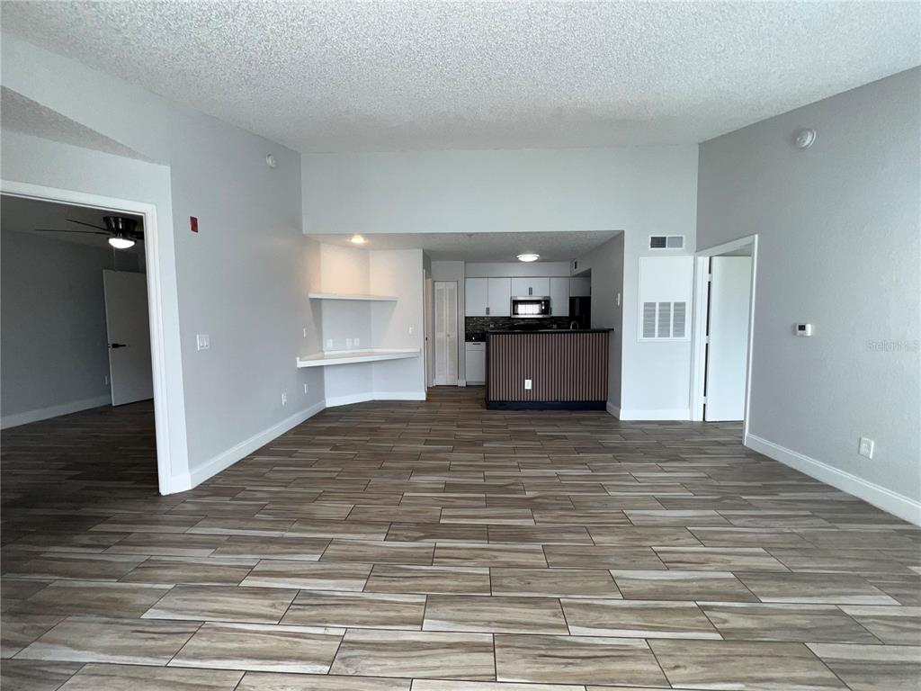 A kitchen features white cabinets, black countertops, a tiled backsplash, and wood-look tile flooring — 2208 ANTIGUA PLACE UNIT 938, KISSIMMEE, FL