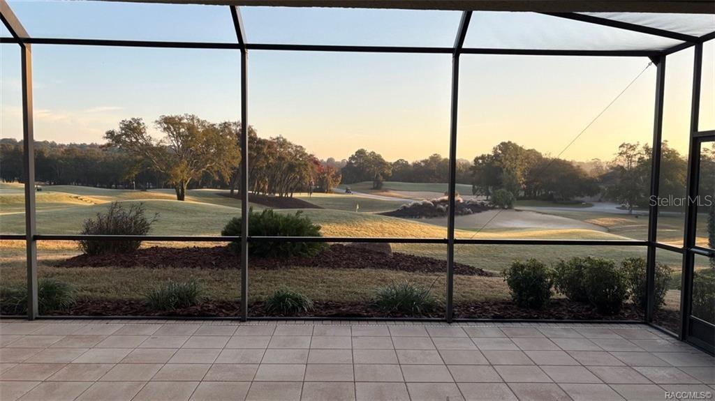 A screened-in patio overlooks a grassy golf course at sunrise — 2618 N CARNOUSTIE LOOP, LECANTO, FL