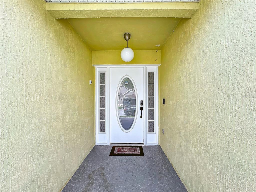 A covered entryway features a white front door with a glass oval insert and sidelights — 458 HOLLINGHEAD LOOP, DAVENPORT, FL