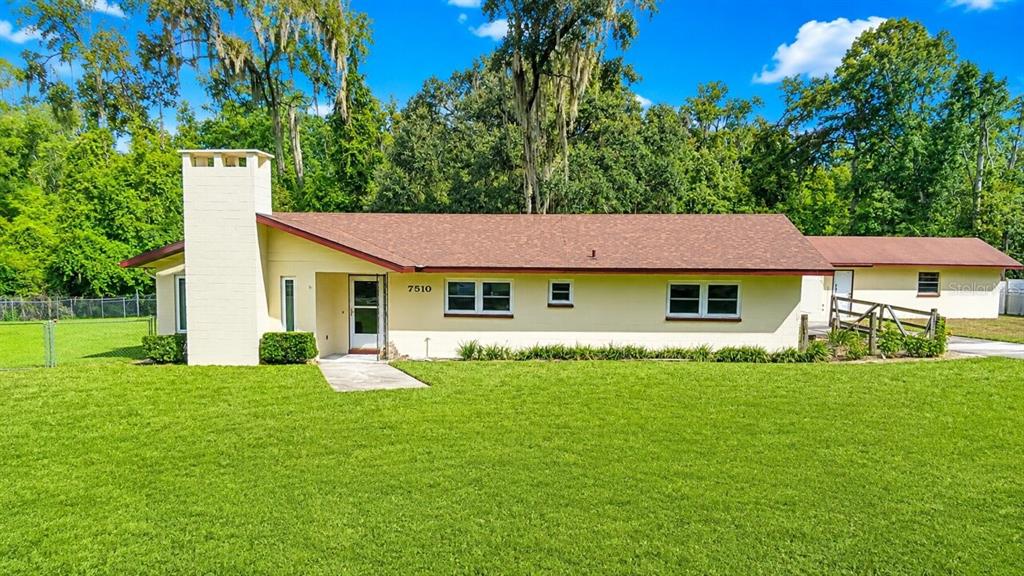A single-story house with a prominent white chimney and a large green lawn — 7510 NW 128TH PLACE, ALACHUA, FL