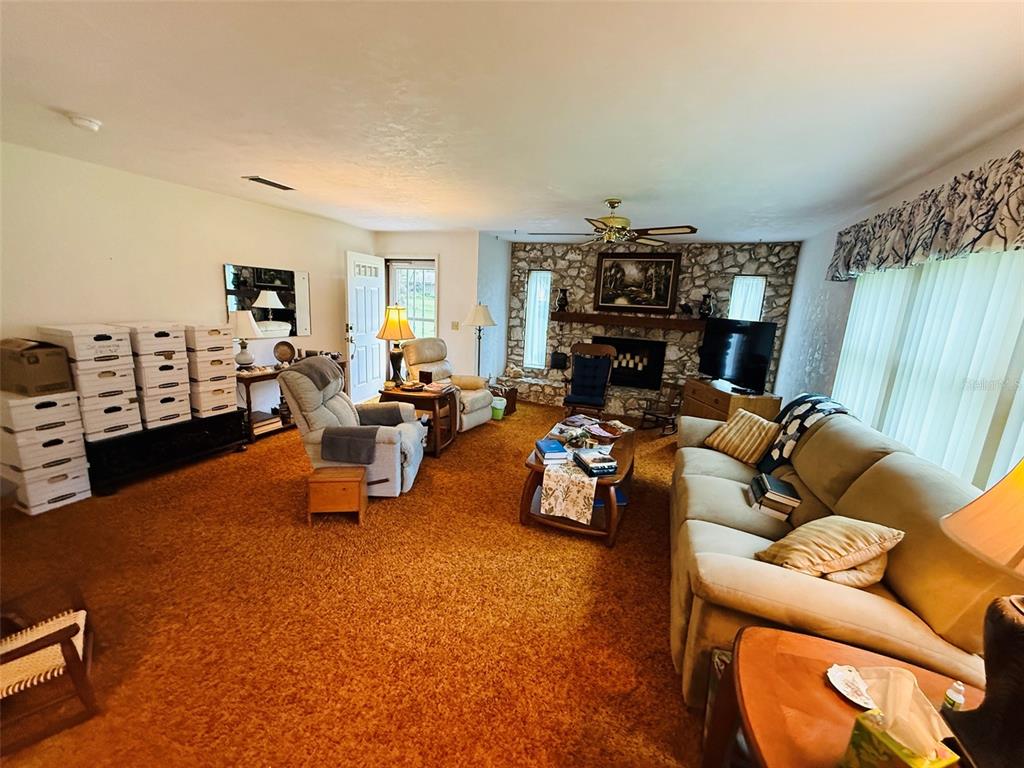 A living room features orange wall-to-wall carpeting, a stone fireplace, and a beige sofa — 7510 NW 128TH PLACE, ALACHUA, FL