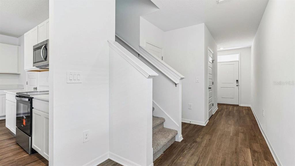 A kitchen area with white cabinets and a staircase leading to an upper level — 5588 TAVERNA LOOP, WINTER HAVEN, FL