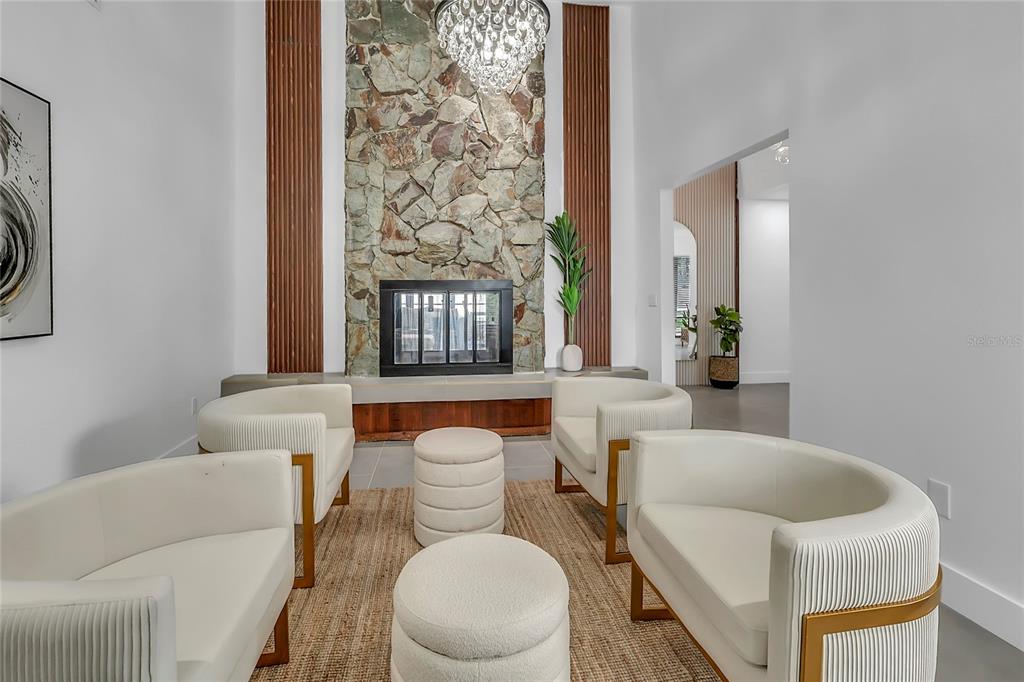 A bright room features four cream-colored chairs, two matching ottomans, and a crystal chandelier — 3033 WISTER CIRCLE, VALRICO, FL