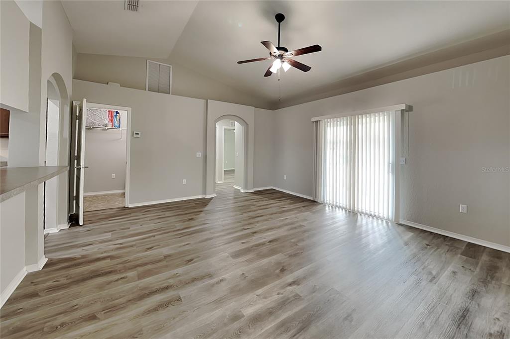 A living room with vaulted ceilings, light gray walls, and wood-look flooring — 495 MAJESTIC GARDENS BOULEVARD, WINTER HAVEN, FL