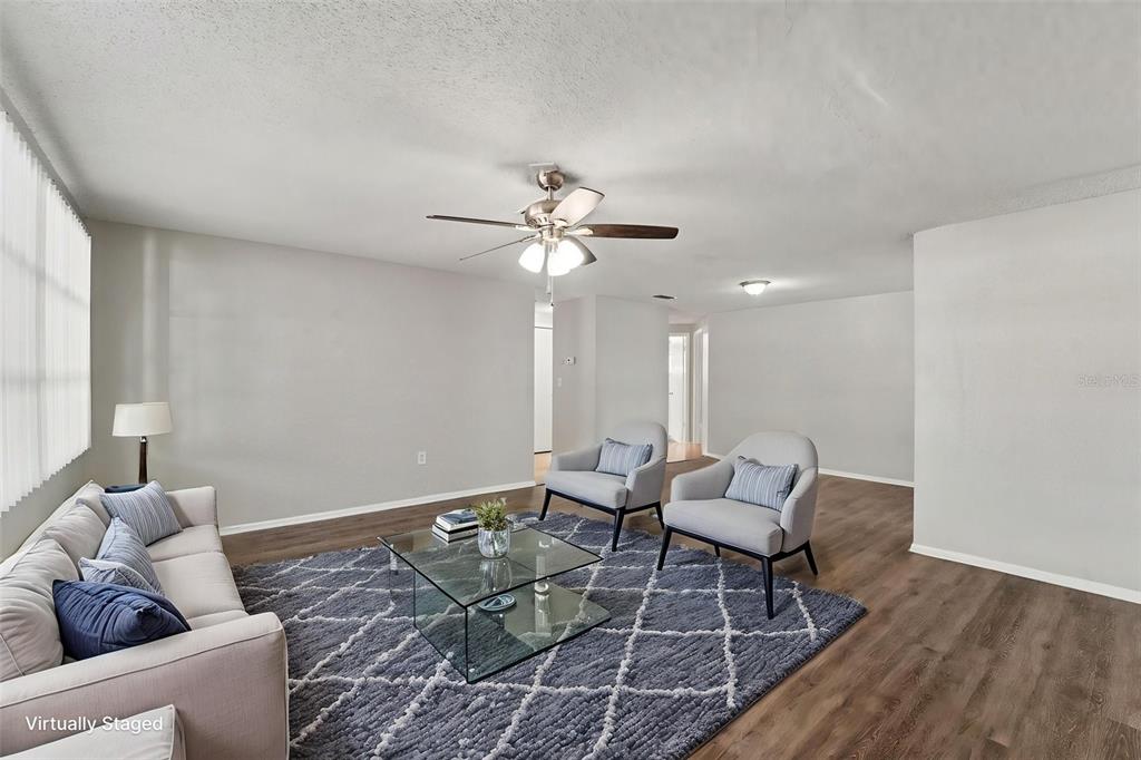 An empty living room with wood-look flooring, a ceiling fan, and light gray walls — 7744 WATERFORD STREET, NEW PORT RICHEY, FL