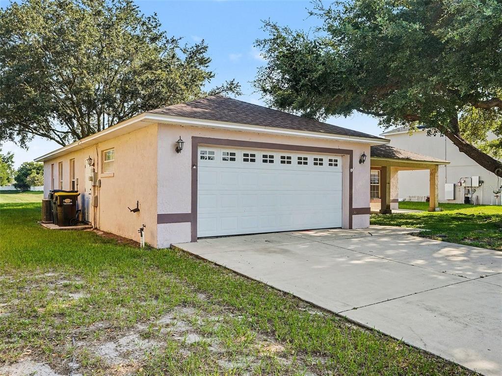 A detached, light-pink garage with a white sectional door sits on a grassy lot — 121 SHADDOCK DRIVE, AUBURNDALE, FL