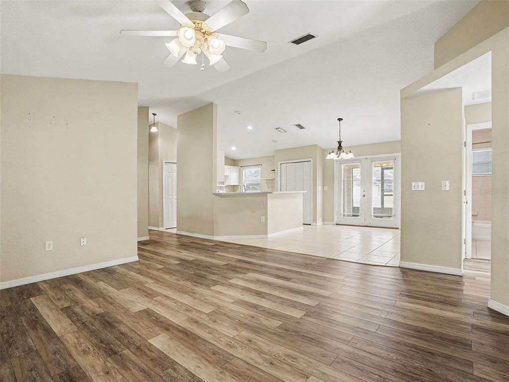 A living room with wood-look flooring transitions into a tiled kitchen and dining area — 121 SHADDOCK DRIVE, AUBURNDALE, FL