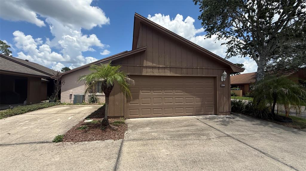 A brown house with a single-car garage, a concrete driveway, and a small palm tree — 250 RAINTREE DRIVE, CASSELBERRY, FL