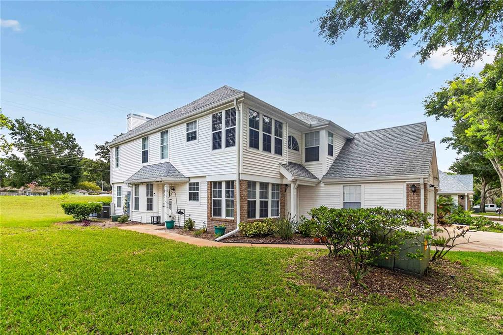 A two-story white siding house with a gray shingled roof and a grassy yard — 4807 COACHMANS DRIVE UNIT 2402, ORLANDO, FL