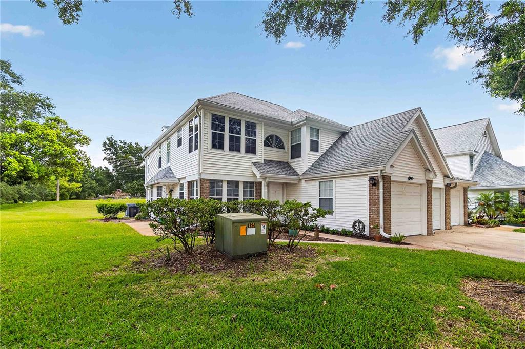 A two-story white siding townhouse with a garage and a green utility box in front — 4807 COACHMANS DRIVE UNIT 2402, ORLANDO, FL