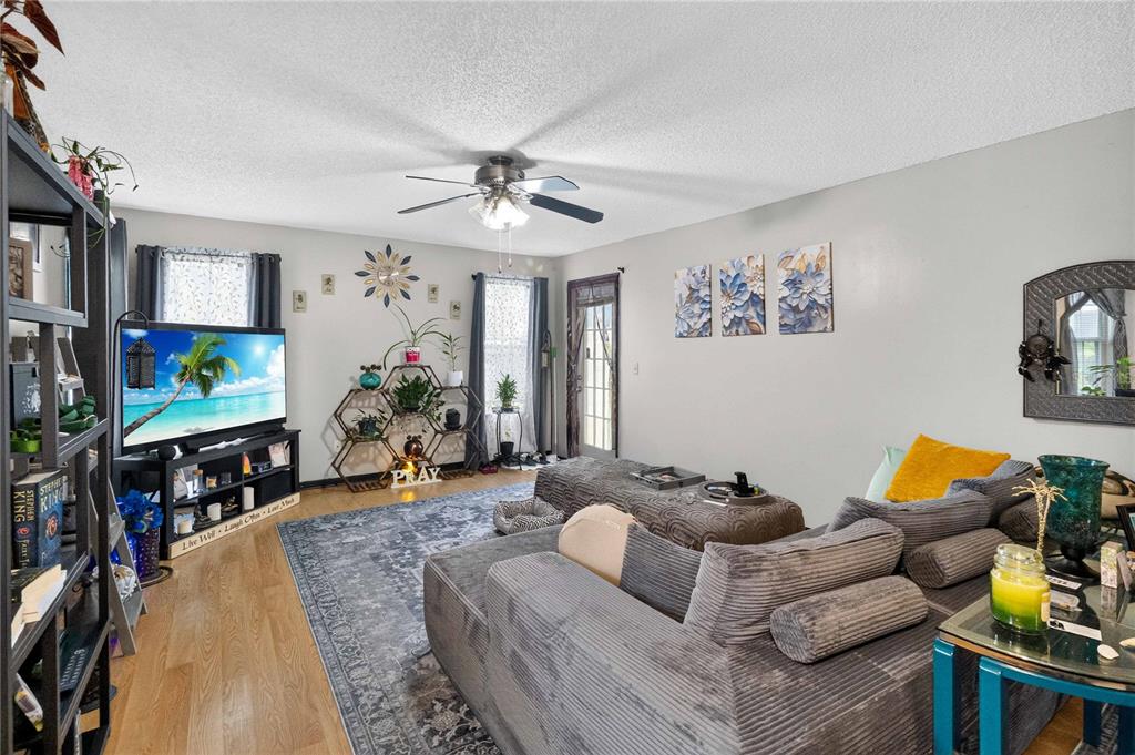 A living room features a grey sectional sofa, a television, and a decorative hexagonal shelf — 4807 COACHMANS DRIVE UNIT 2402, ORLANDO, FL