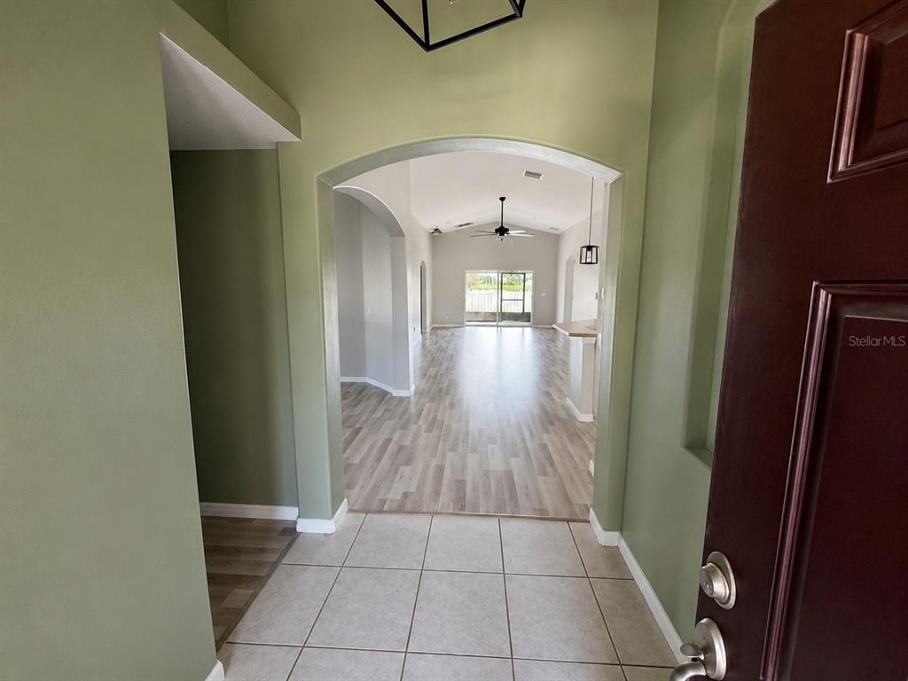 An entryway with tile flooring leads into a living area with wood-look floors and arches — 2242 COLVILLE CHASE DRIVE, RUSKIN, FL