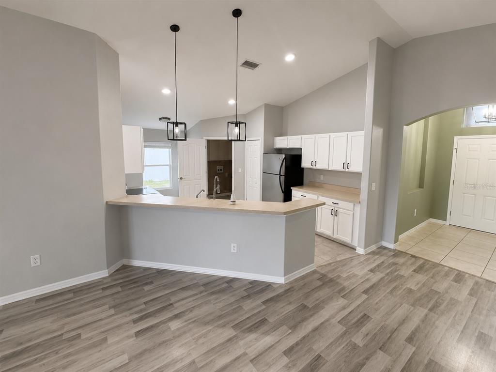 A kitchen with white cabinets, a breakfast bar, and light wood-look flooring — 2242 COLVILLE CHASE DRIVE, RUSKIN, FL