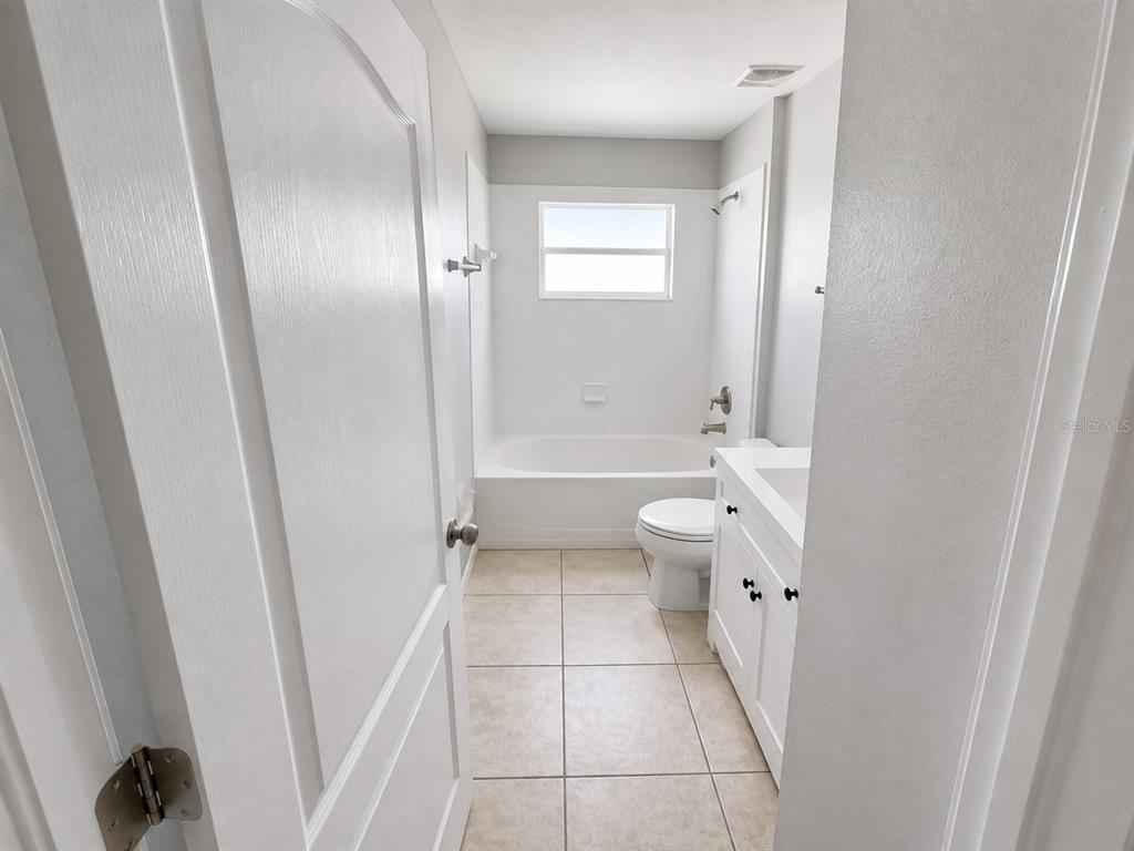 A bathroom features a white vanity, a toilet, and a bathtub with a shower head — 2242 COLVILLE CHASE DRIVE, RUSKIN, FL